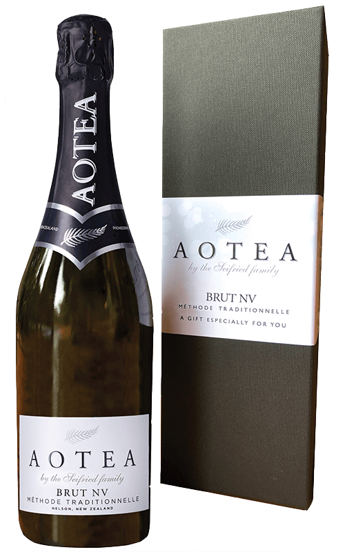 Aotea by Seifried Brut NV Methode Traditionnelle sparkling wine next to its green gift box packaging on a transparent background