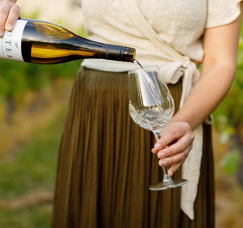 Pouring a glass of Aotea by Seifried Nelson Chardonnay outdoors in the vineyard