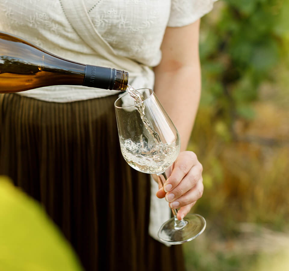 Close-up of Seifried Nelson Chardonnay white wine being poured into a wine glass outdoors