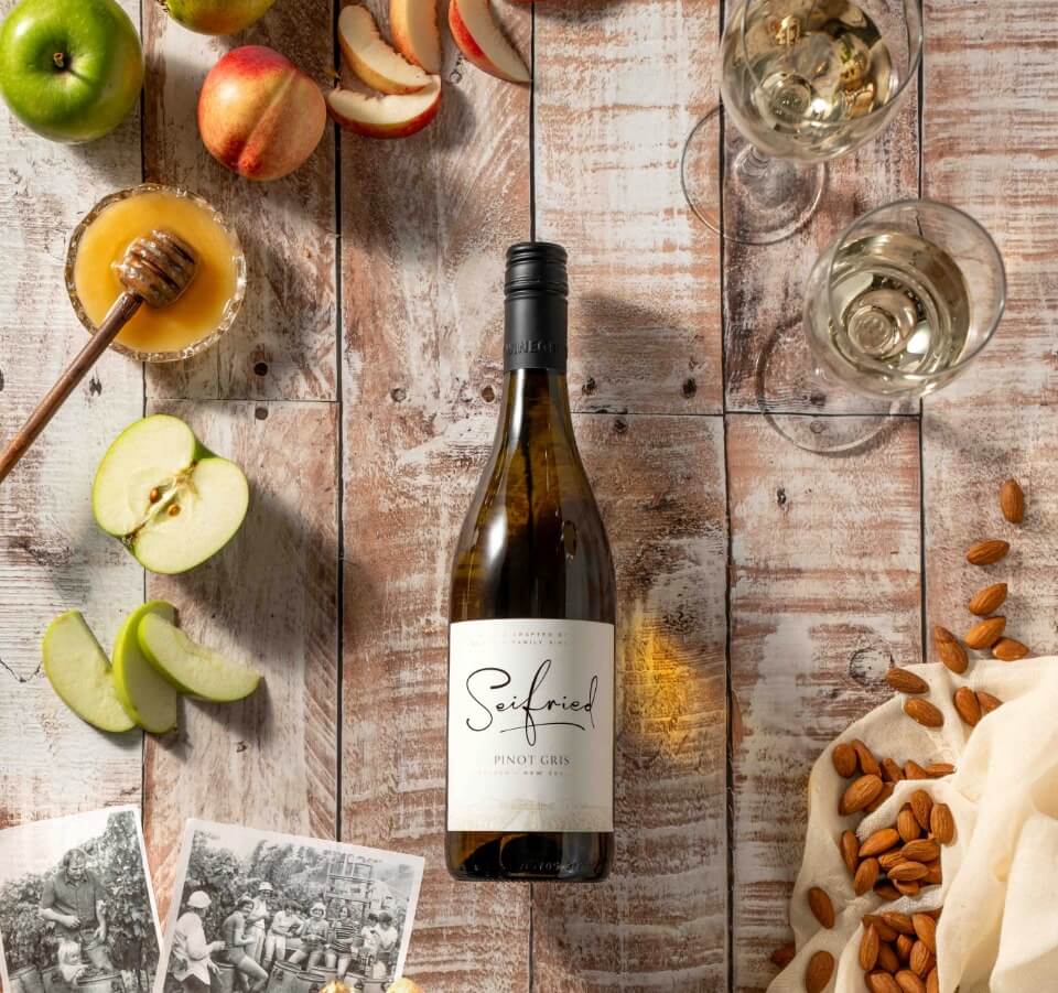 Bottle of Seifried Nelson Pinot Gris styled with fresh sliced pears and peaches to highlight its stone fruit flavours
