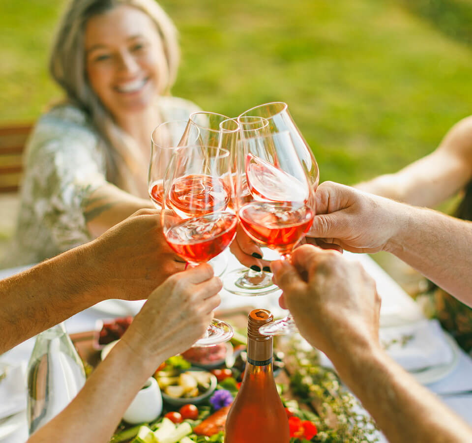 People clinking glasses of Seifried Nelson Rosé at an outdoor dining table"