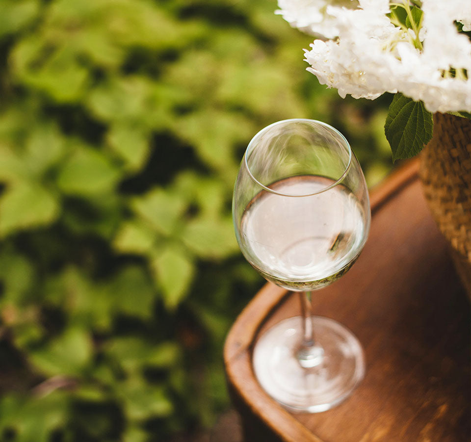 Glass of Seifried Winemakers Collection Barrique Fermented Chardonnay on a wooden table outdoors